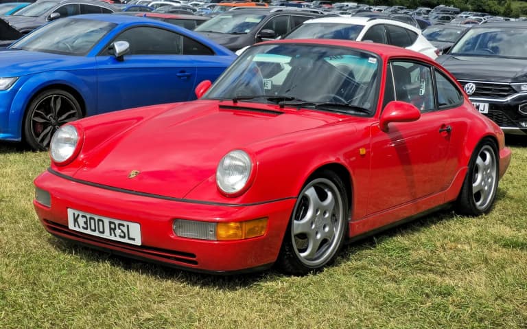 Red 1992 Porsche 911 Carrera 2 (964) parked on grass.