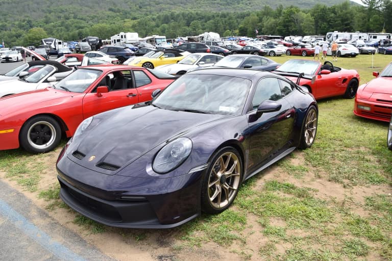 Dark blue Porsche 911 GT3 (992) parked on grass at a car show.