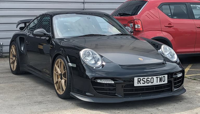 Black 2010 Porsche 911 GT2 RS (997) with gold wheels.