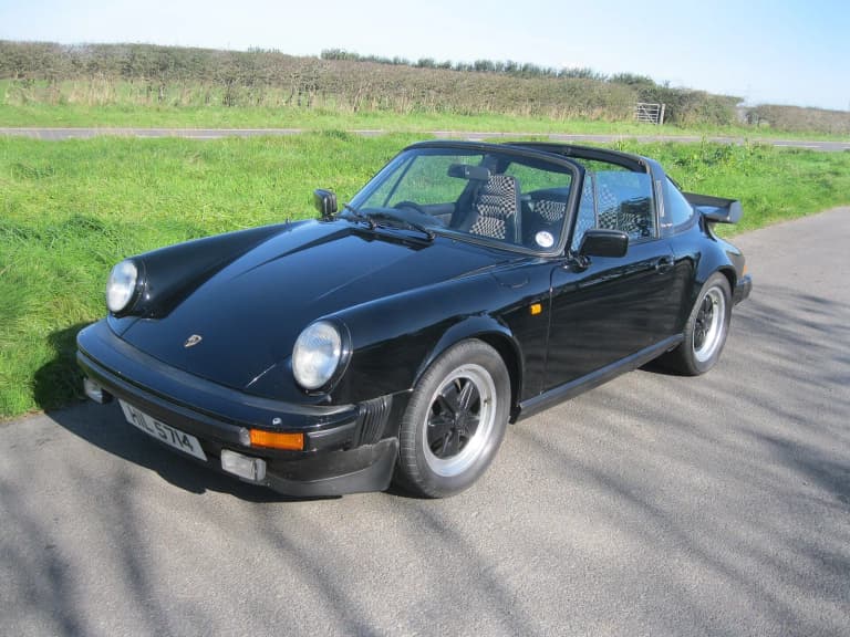 Black 1982 Porsche 911 SC Targa parked on a quiet country road.
