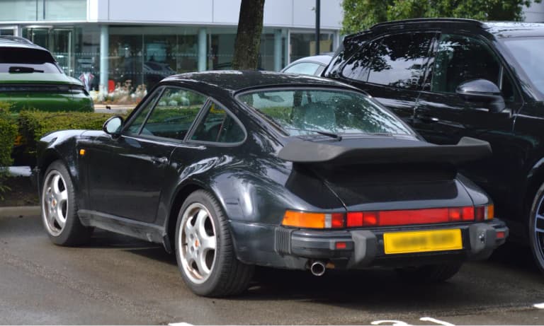 Black Porsche 964 Turbo parked outside a dealership
