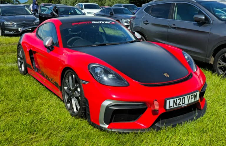 Red Porsche 718 GT4 in front three-quarter view on grass