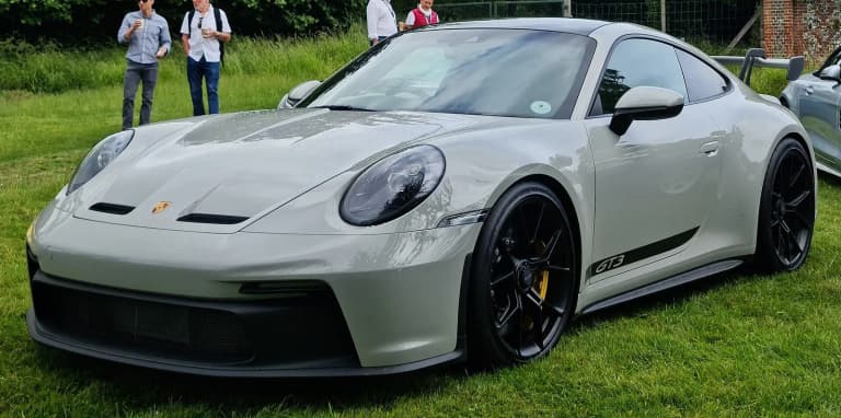 Grey Porsche 911 (992) GT3 parked on grass at a car show.