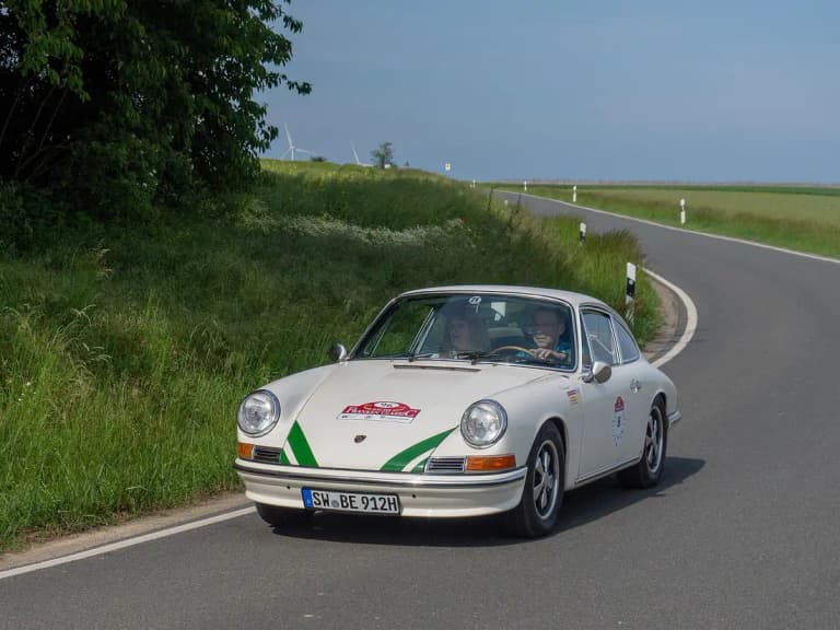 White Porsche 912 coupe driving on a country road