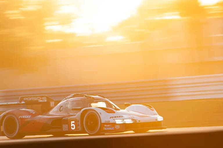 Number 5 Porsche 963 racing into a golden sunset during an endurance event