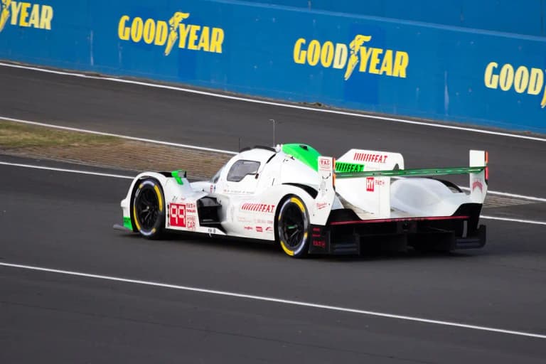 White and green F.A.T. Proton Competition Porsche 963 number 99 from the rear at Le Mans