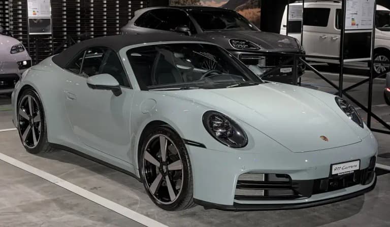 Chalk-colored Porsche 992 911 Carrera Cabriolet with the soft top raised, front three-quarter view