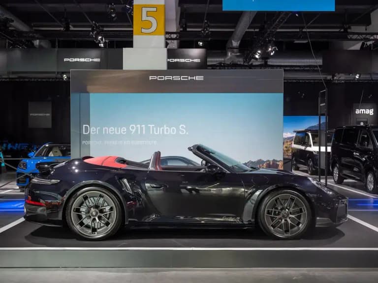Dark blue Porsche 911 Turbo S Cabriolet with a red leather interior and the roof folded down