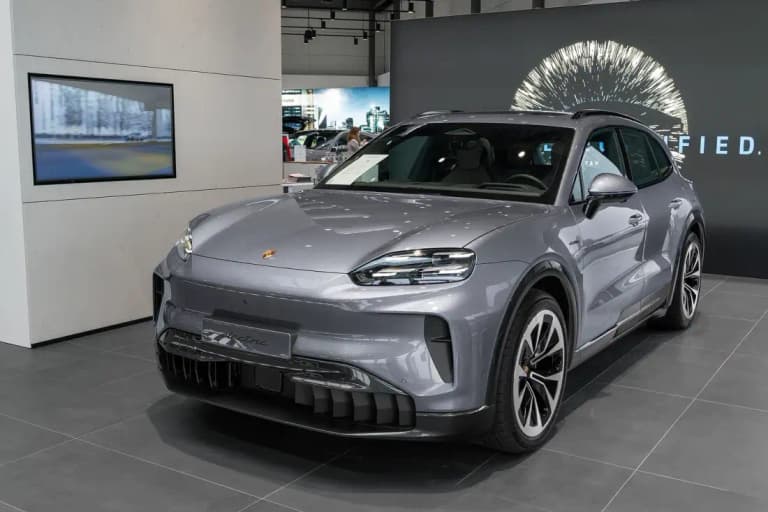 Gray Porsche Cayenne Electric in a showroom with an electric badge on the nose