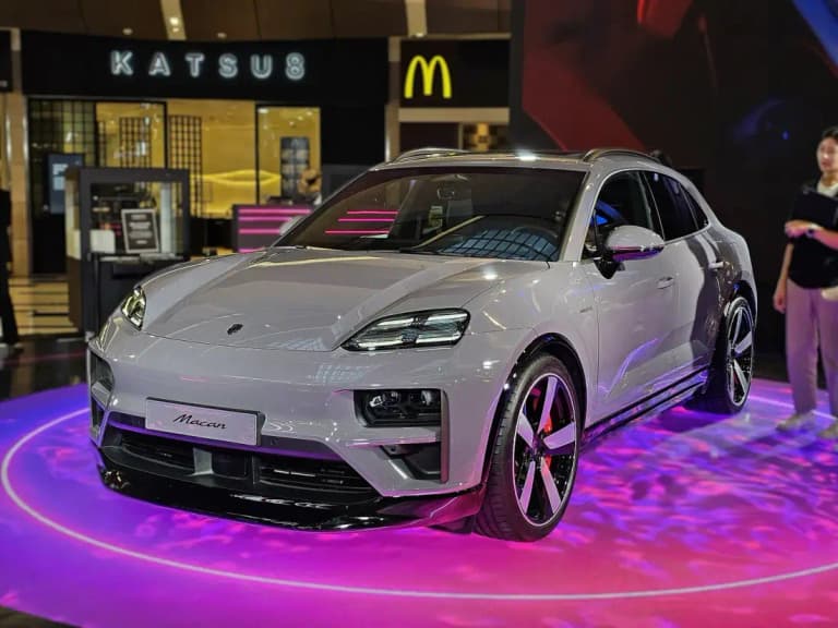 Gray Porsche Macan Electric displayed on a lit stand in a shopping mall