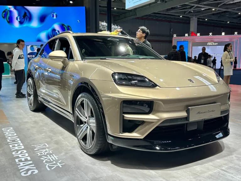 Gold Porsche Macan Turbo Electric on display at an auto show