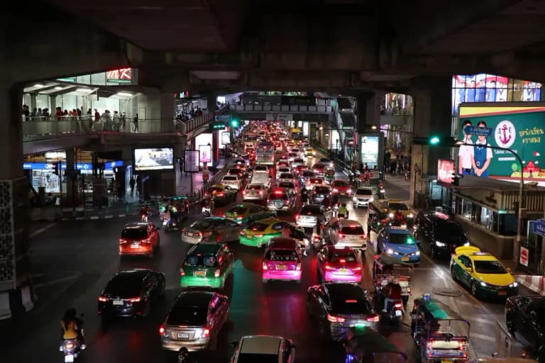 Evening traffic queueing under the BTS tracks at the Siam intersection in Bangkok