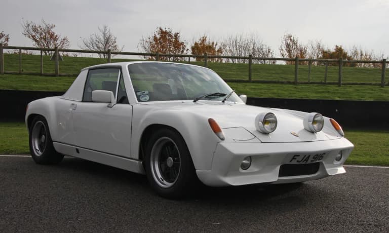 White Porsche 916 viewed from the side, showing its fixed steel roof, flared fenders, and wide Fuchs wheels