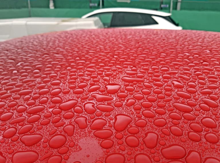 Water beading on a freshly polished red car roof