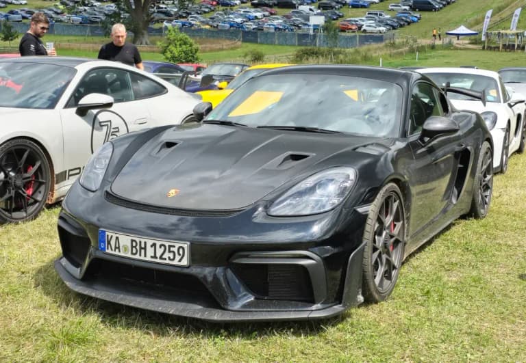 Black Porsche 718 Cayman GT4 RS coupe with rear wing at a festival