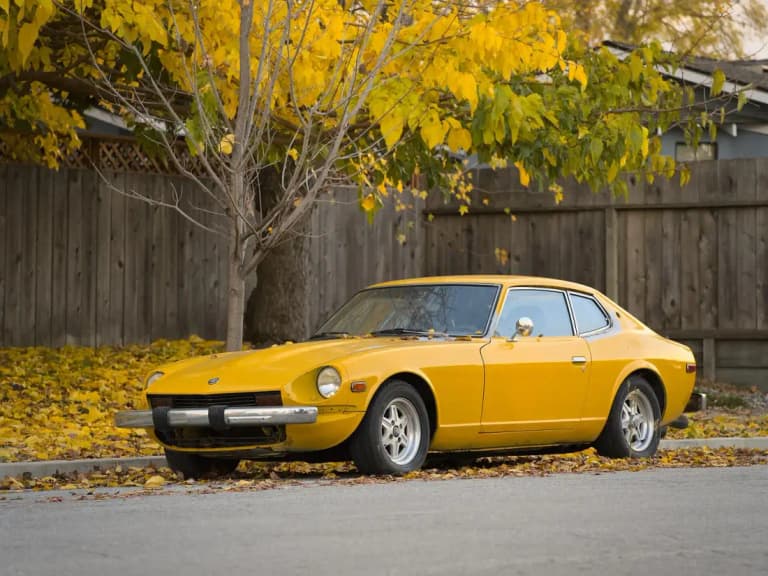 Yellow classic Datsun Z coupe parked under autumn trees