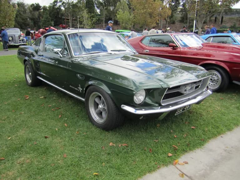 Dark green 1967 Ford Mustang fastback on grass at a classic car show