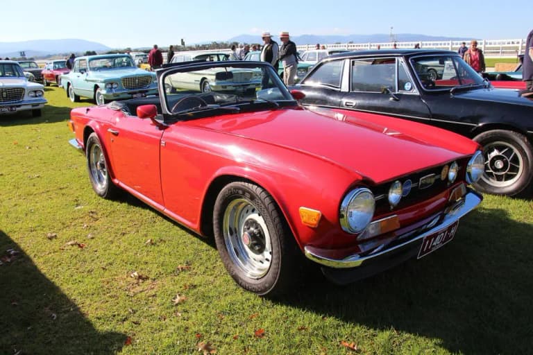 Red Triumph TR6 convertible roadster parked on grass
