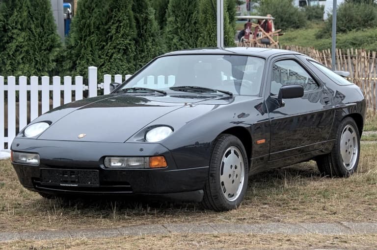 Black Porsche 928 coupe parked on grass
