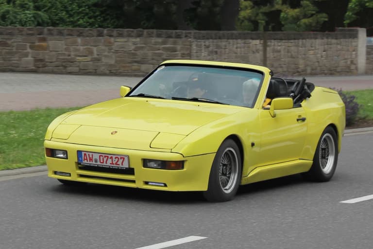 Yellow Porsche 944 cabriolet driving with the top down