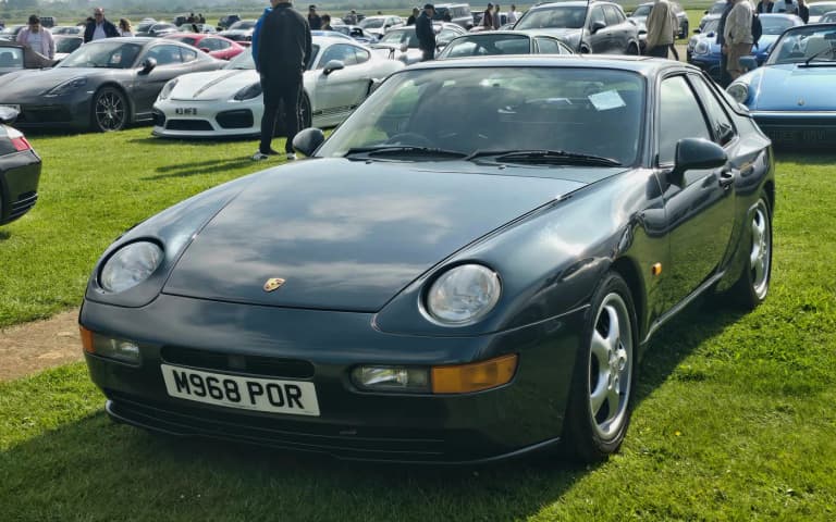 Dark green Porsche 968 coupe parked on grass, front three-quarter view