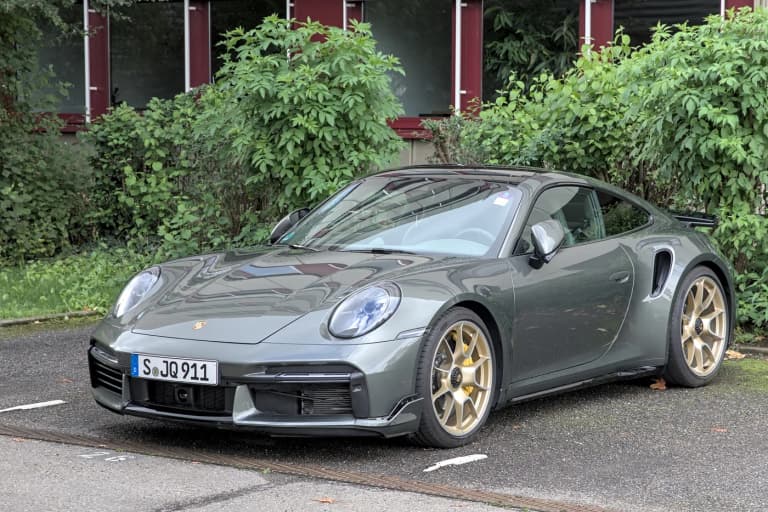 Dark gray Porsche 992 Turbo S coupe with gold wheels