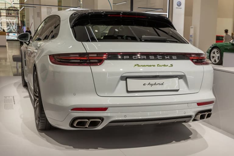 White Porsche Panamera Turbo S E-Hybrid Sport Turismo rear view showing quad exhaust tips at a motor show