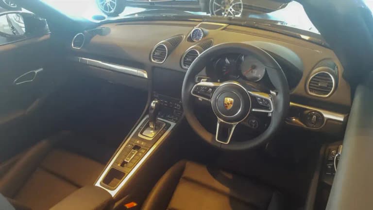 Porsche 718 Boxster interior with the Sport Chrono mode dial on the steering wheel and the dashboard clock