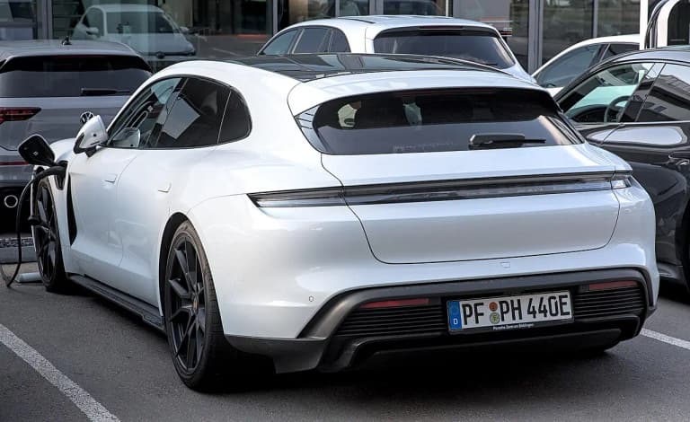 White Porsche Taycan Sport Turismo GTS rear view plugged in to charge