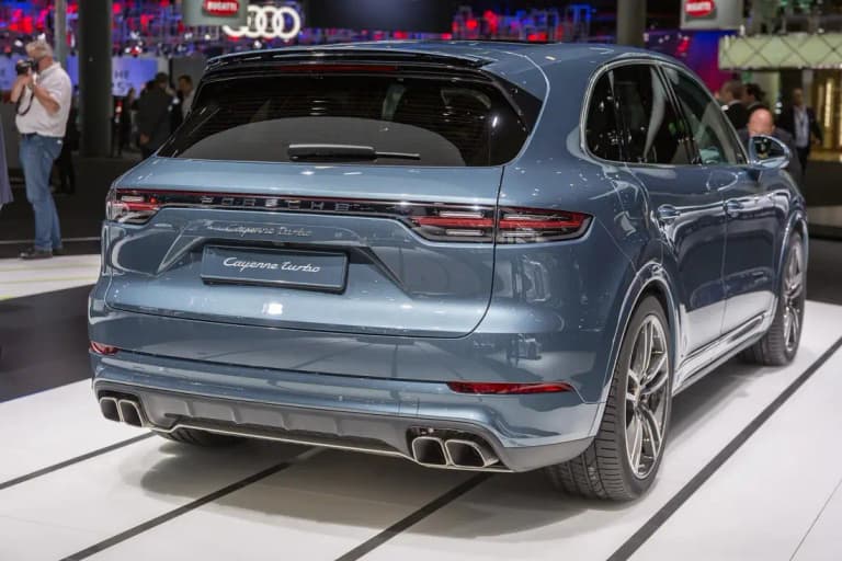 Blue-grey Porsche Cayenne Turbo rear three-quarter view at a motor show