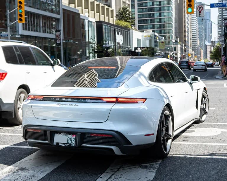 Light blue Porsche Taycan Turbo rear three-quarter view on a city street