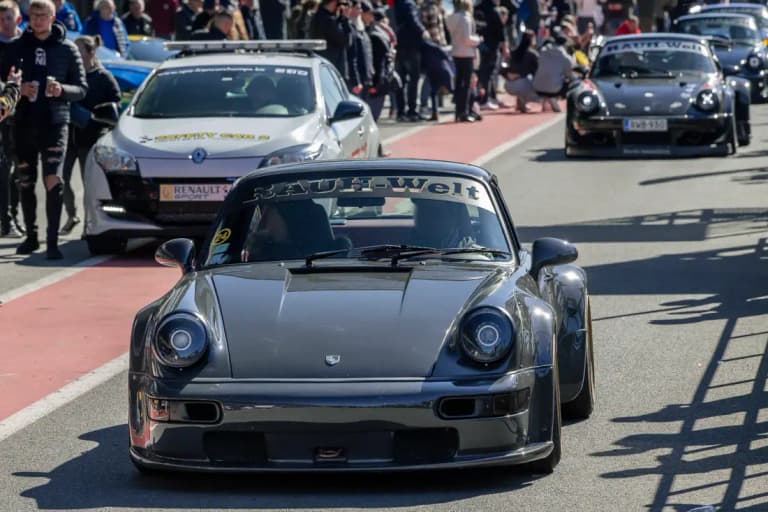 Gunmetal RWB Porsche named Bourgogne in a pit lane with another RWB behind