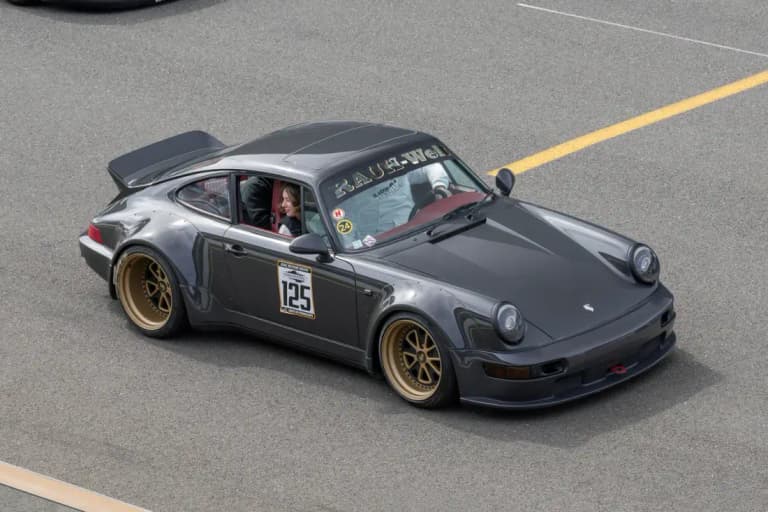 Gunmetal RWB Porsche 964 with gold wheels driving on track
