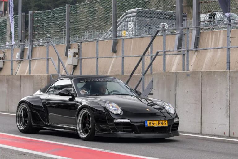 Black RWB Porsche 997 Carrera S Cabriolet with widebody arches in a pit lane