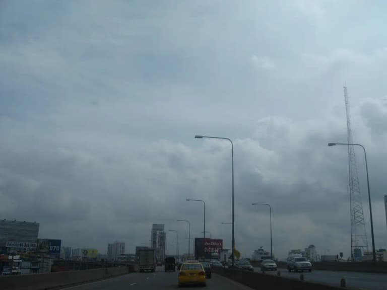 Cars driving on Bangkok's elevated Don Muang Tollway (Uttaraphimuk Expressway) under a cloudy sky