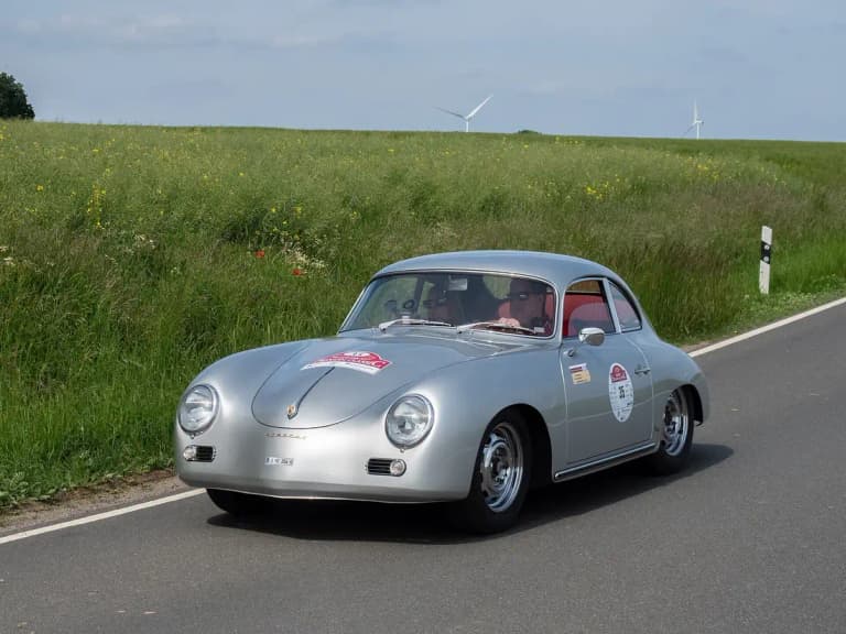 Silver Porsche 356 A coupe driving on a country road