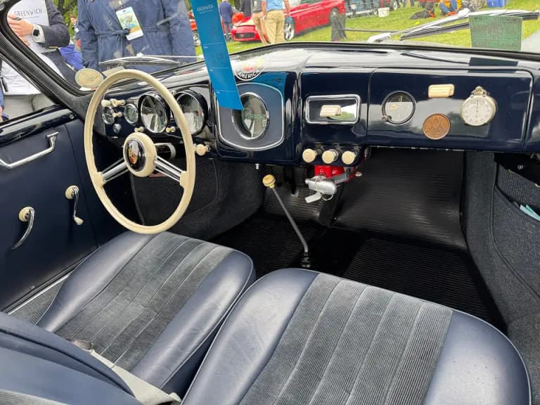 Porsche 356 interior with ivory steering wheel, round gauges, and blue seats
