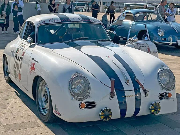 White Porsche 356 pre-A 1500 coupe with blue racing stripes and mesh headlight covers