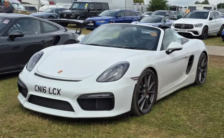 White Porsche 981 Boxster Spyder with the roof removed parked on grass