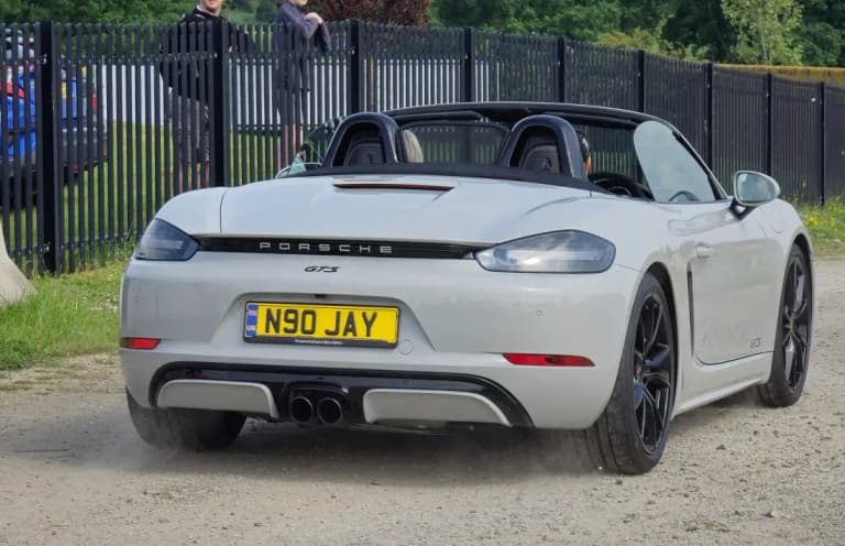 Gray Porsche 718 Boxster GTS rear view with the roof down