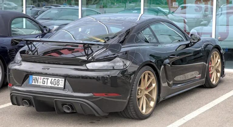 Black Porsche 718 Cayman GT4 with gold wheels and fixed rear wing