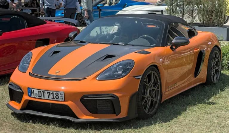 Orange Porsche 718 Spyder RS front three quarter view with black soft top up