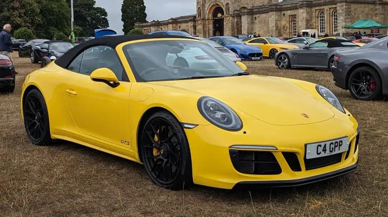 Yellow Porsche 991 Carrera GTS Cabriolet with the roof up, black wheels and yellow brake calipers