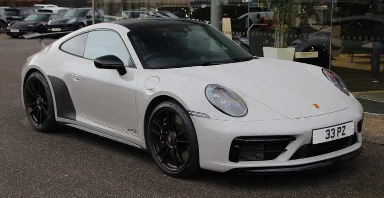 White Porsche 992 Carrera GTS coupe with a rear wing, black wheels and GTS side badge