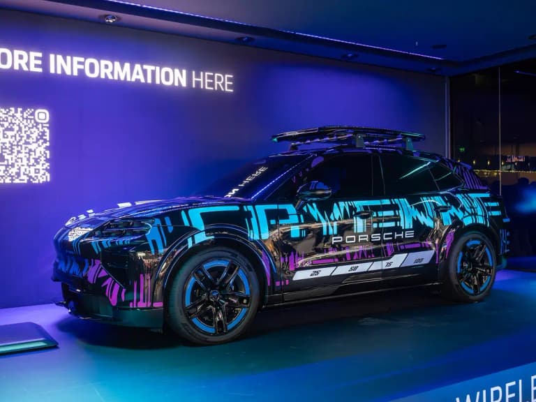 Camouflaged Porsche Cayenne Electric prototype on a wireless charging display stand