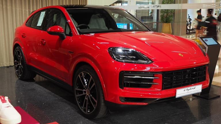 Red Porsche Cayenne E-Hybrid Coupe, front three-quarter view in a showroom