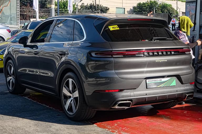 Grey Porsche Cayenne E-Hybrid facelift, rear three-quarter view with the Cayenne badge