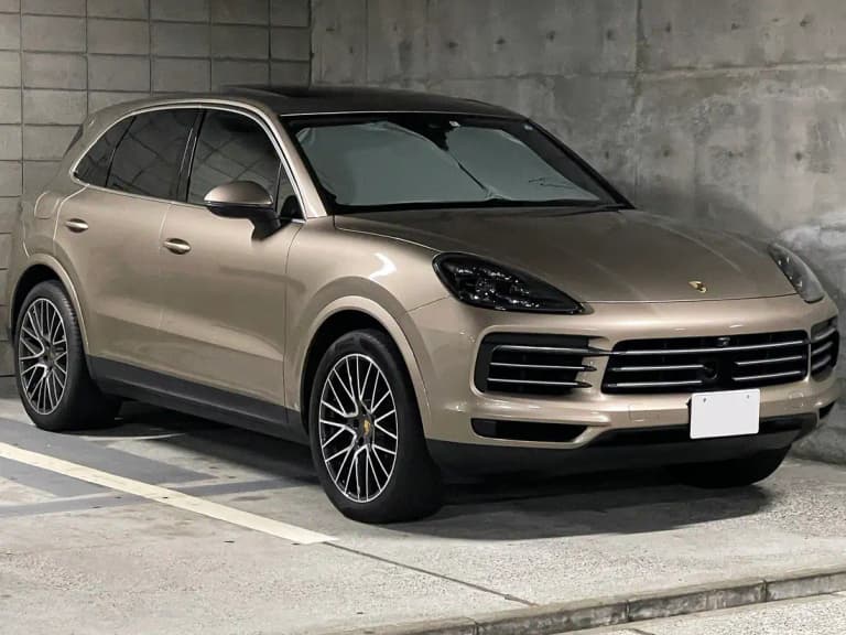 Bronze third-generation Porsche Cayenne S (9YA), front three-quarter view parked by a concrete wall