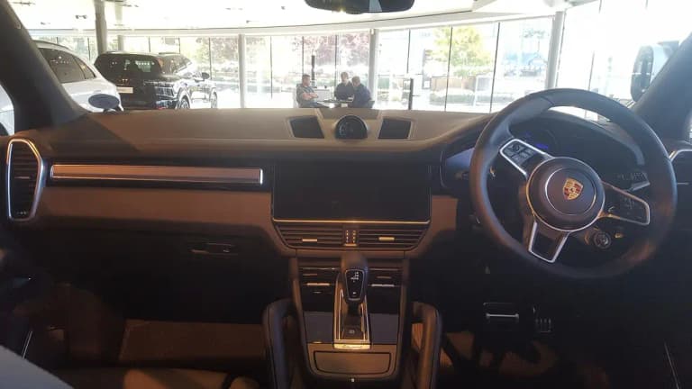 Porsche Cayenne S interior showing the digital instruments, central touchscreen, and Cayenne S console badge