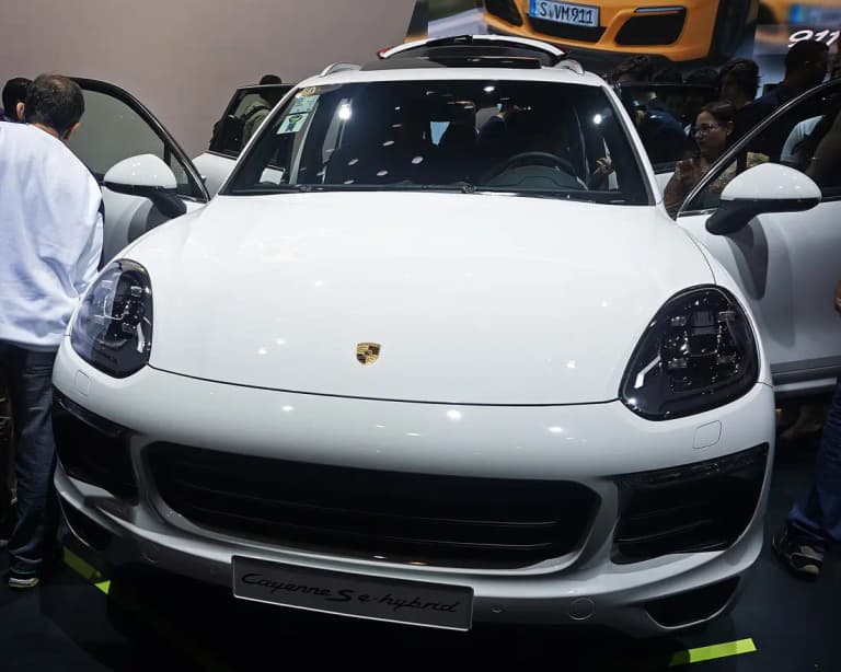 White Porsche Cayenne S E-Hybrid with the S e-hybrid badge on the front plate at a motor show